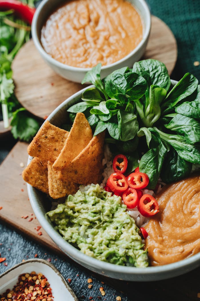 Delicious vegan bowl featuring guacamole, spinach, chili, and tortilla chips for a healthy meal.